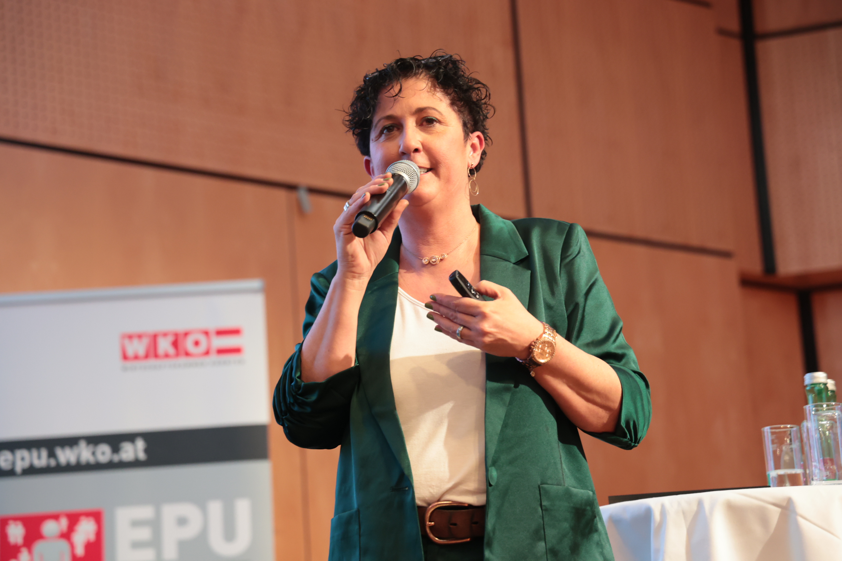 Nicole Mayer auf der Bühne mit Mikrofon und Presenter in der Hand.